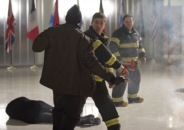 John (Jim Caviezel) habillé en pompier se bat et Lionel (Kevin Chapman) surveille ses arrières